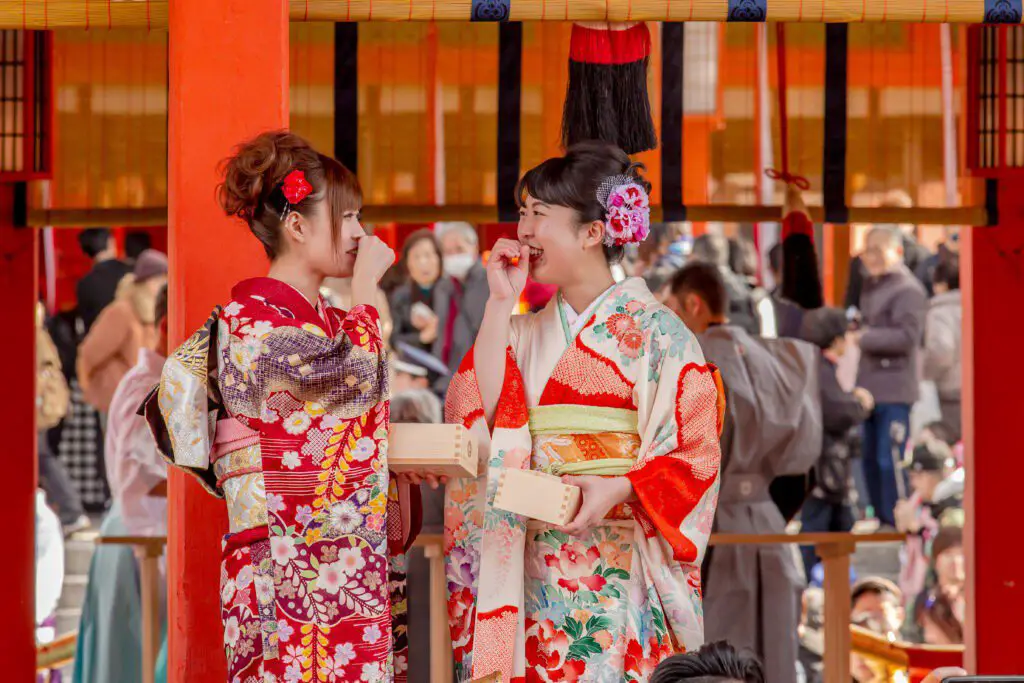 Two Japanese women in Kimono laugh at Fushimi Inari Taisha in Kyoto.