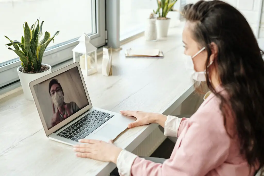 Woman wearing facemask having a video call. Featured image for italki Review article.