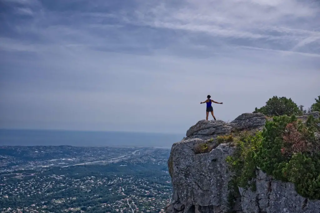 A woman on the edge of a cliff, overlooking a city. Featured image for language learning goals article.