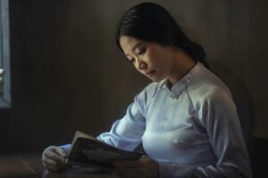 A picture of an East Asian woman in a white blouse reading a book. Featured image for introduction to Chinese philosophy article